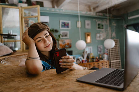 Young woman artist using gadgets while resting at her studio indoorsの写真素材