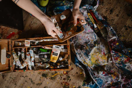 Young white woman mixing oil paints while working in her studio