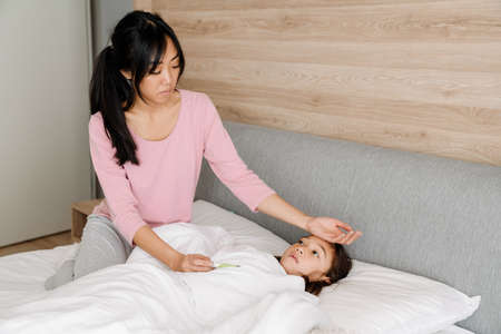 Asian woman taking care of her daughter with flu at home