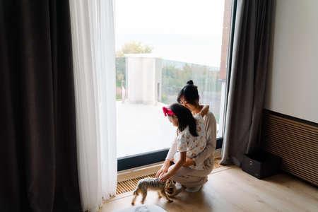 Asian family playing with their dog while spending time together at homeの写真素材