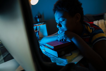 Black boy sleeping by computer monitor during doing at home