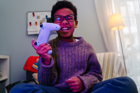 Black boy laughing while using joystick while playing online game at home