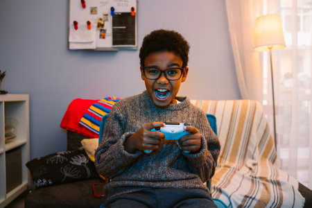 Black boy screaming while using joystick while playing online game at homeの写真素材