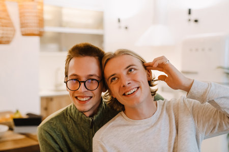 European gay couple hugging and smiling while spending time together at homeの写真素材