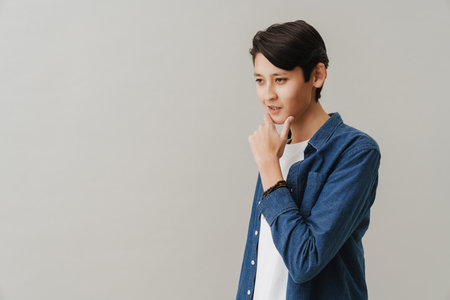 Asian boy wearing shirt posing and looking aside isolated over white backgroundの写真素材