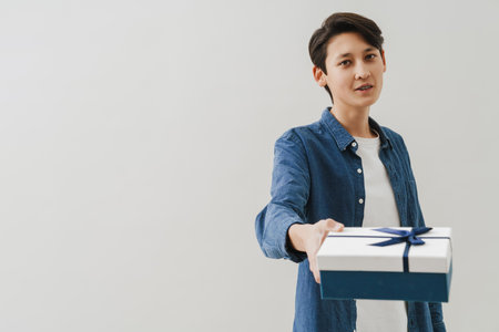 Asian boy with dental braces smiling while posing with gift box isolated over white backgroundの写真素材