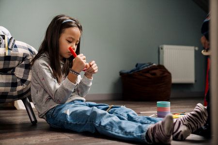 Asian preteen girl playing while sitting on floor at homeの写真素材