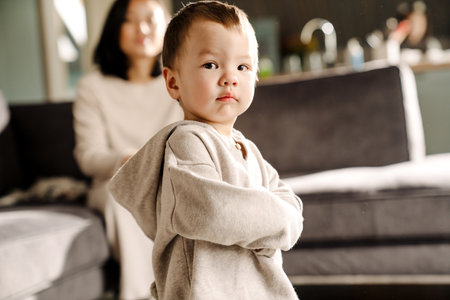 Asian boy looking at camera while spending time with her mother at homeの写真素材