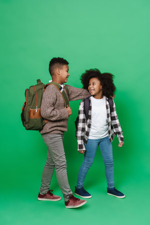 Black boy and girl hugging while walking together isolated over green backgroundの写真素材