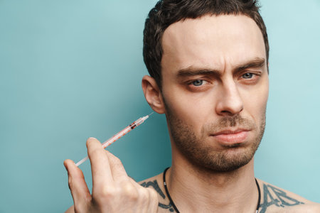 Mid aged brunette man getting facial treatment over blue wall backgroundの写真素材