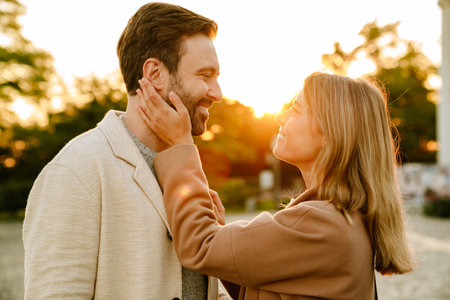 White romantic couple smiling and hugging while walking in autumn park