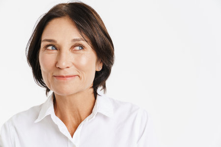 Mature brunette woman smiling and looking aside isolated over white backgroundの写真素材