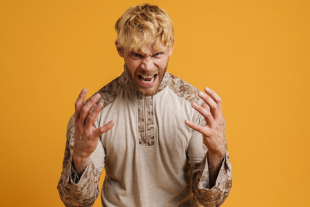 White furious military man screaming while gesturing isolated over yellow backgroundの写真素材