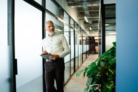 Grey white man wearing shirt working with tablet computer in officeの写真素材