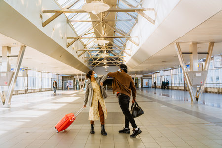 Indian couple wearing face masks elbows bumping in airport indoorsの写真素材