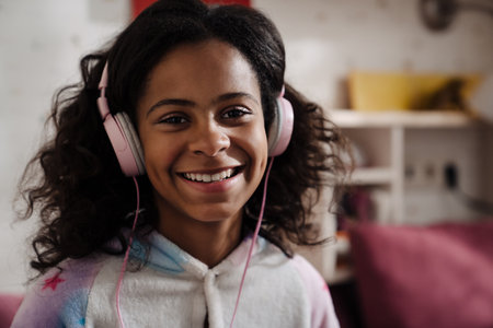 Portrait of happy african girl in headphones listening to the music in her room at homeの写真素材