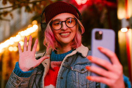 Young woman listening music and using cellphone while walking at city streetの写真素材