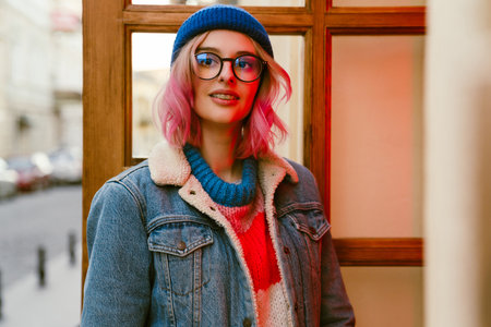 Young white woman in eyeglasses smiling at camera while standing by door outdoorsの写真素材