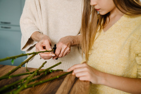 White senior woman making bouquet with her granddaughter in kitchen at homeの写真素材