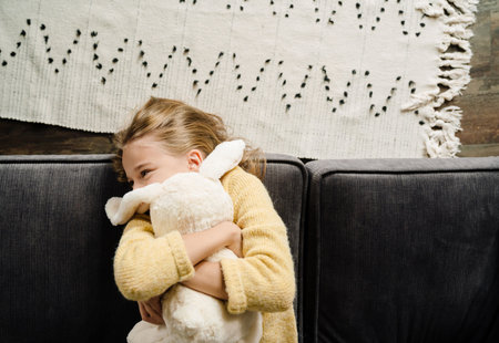 White happy girl making fun with toy while lying on couch at homeの写真素材