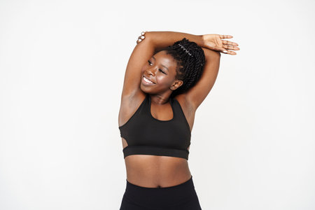 Black young woman doing exercise while working out isolated over white backgroundの写真素材