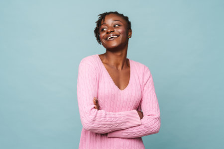 African american happy woman smiling and standing with arms folded isolated over blue backgroundの写真素材
