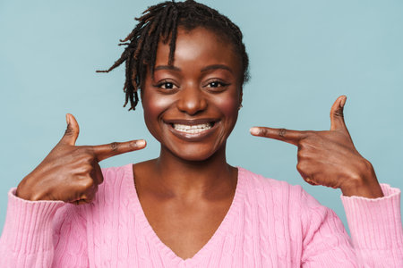 African american happy woman laughing and pointing at her smile isolated over blue backgroundの写真素材