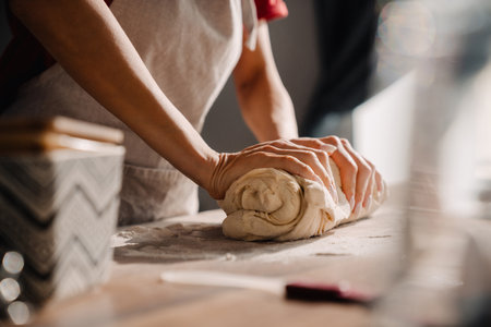 Young woman wearing apron cooking and kneading dough in kitchen at homeの写真素材