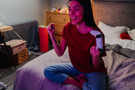 Young hispanic woman making winner gesture while playing online game at home