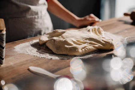 Young woman wearing apron cooking and kneading dough in kitchen at home