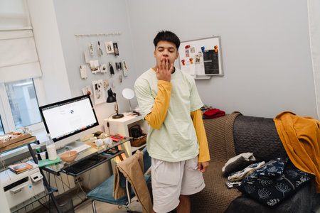 Brunette teenage boy wearing pajama yawning after sleep in bedroom