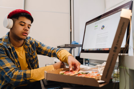 Middle-eastern teenage boy using desktop computer while studying at homeの写真素材