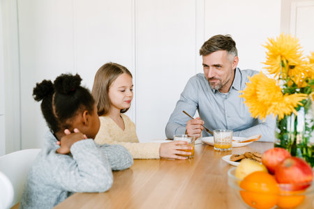 Smiling father having breakfast with interracial daughters. Adoption concept.の写真素材