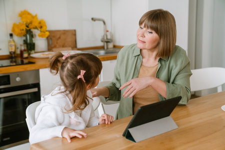 White girl using tablet computer while spending time with her grandmother at homeの写真素材