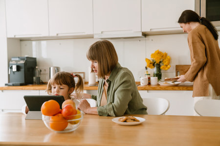 White girl using tablet computer while spending time with her family at homeの写真素材