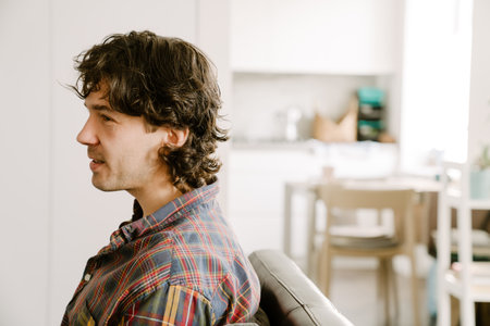 White man wearing shirt smiling while resting on couch at homeの写真素材