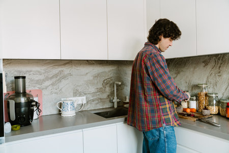 White man wearing shirt cutting vegetables while cooking lunch in kitchen at home