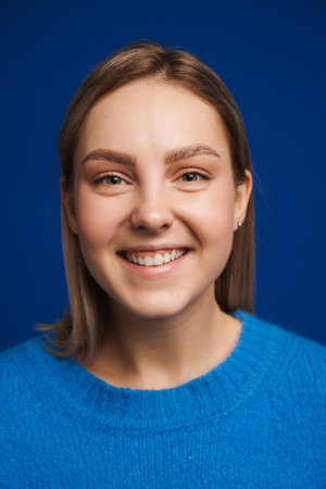 Portrait of young beautiful happy smiling girl looking in camera over blue isolated background