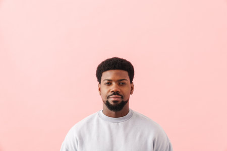 Black mid man with beard posing and looking at camera isolated over pink background