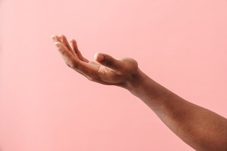 Photo of black man's hand holding copyspace isolated over pink backgroundの写真素材