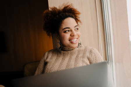 Young beautiful happy smiling african woman with laptop looking rightward