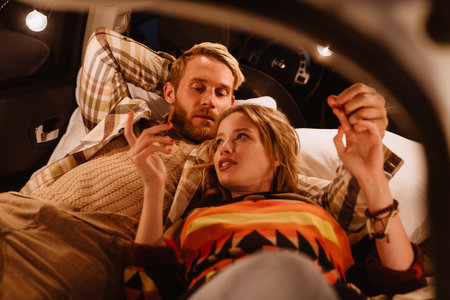 Happy young white couple smiling and lying together in car outdoorsの写真素材