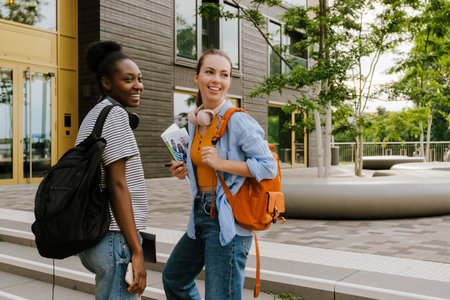 Young multiracial women smiling and talking while standing by campus together outdoorsの写真素材