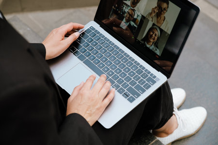Mature woman working with laptop while sitting on stair indoorsの写真素材
