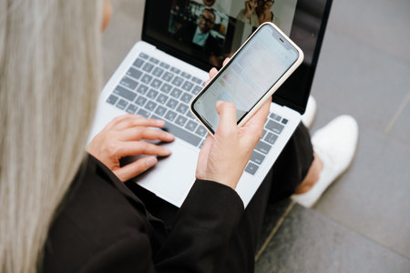 Mature woman using gadgets while sitting on stair indoorsの写真素材