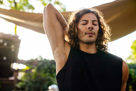 Young curly white man doing workout and stretching his body outdoorsの写真素材