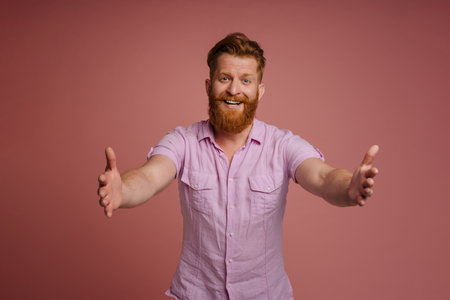 Ginger white man smiling and stretching his hands at camera isolated over pink backgroundの写真素材
