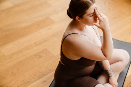 Ginger young woman meditating during yoga practice indoorsの写真素材