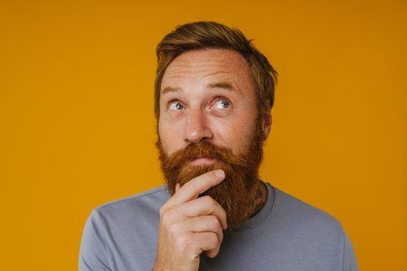 Bearded happy man posing at camera while standing isolated over yellow backgroundの写真素材