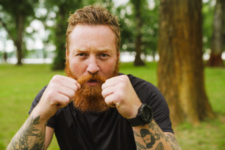Ginger bearded man doing exercise during workout in park outdoorsの写真素材